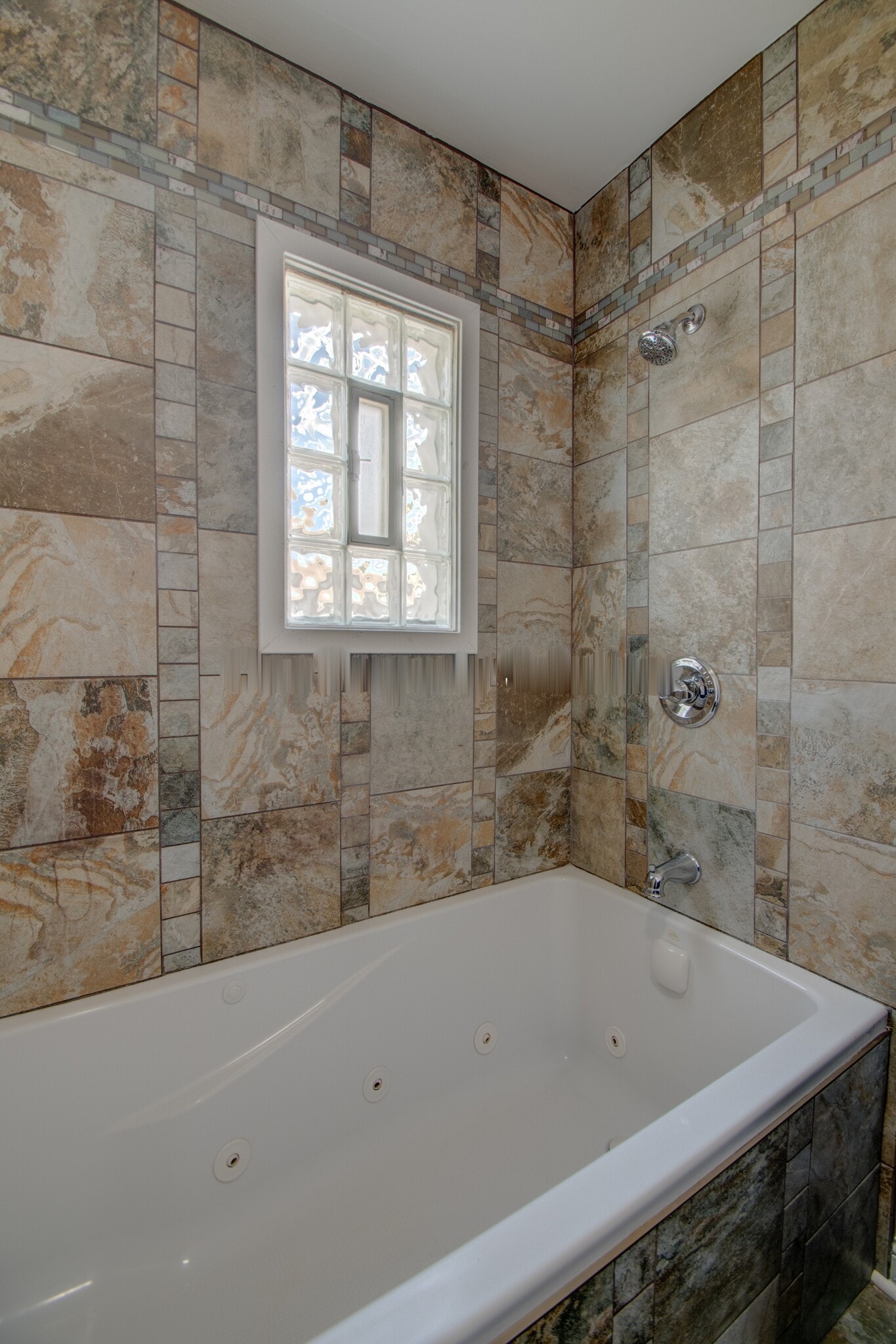 Deep white jetted tub with stone-look wall tile